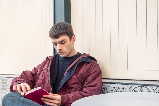young-man-reads-book-coffee-shop-reading-book-outdoors